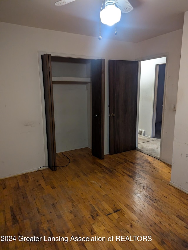 unfurnished bedroom with hardwood / wood-style floors, ceiling fan, and a closet