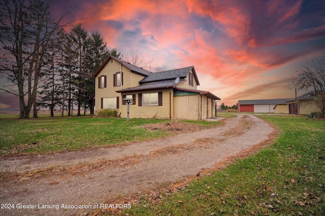 property exterior at dusk featuring solar panels, a yard, and a garage