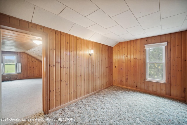 bonus room featuring carpet, wooden walls, and vaulted ceiling