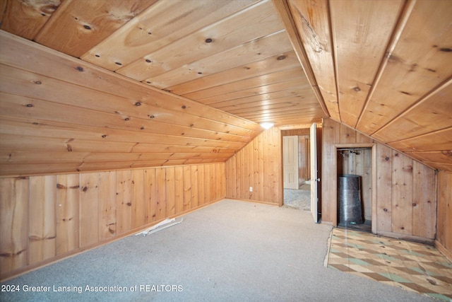 bonus room with light carpet, wooden walls, and vaulted ceiling