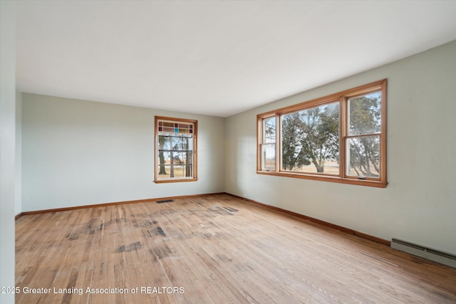 unfurnished room featuring a baseboard radiator, visible vents, baseboards, and wood finished floors