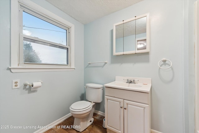 half bath with baseboards, a textured ceiling, toilet, and vanity