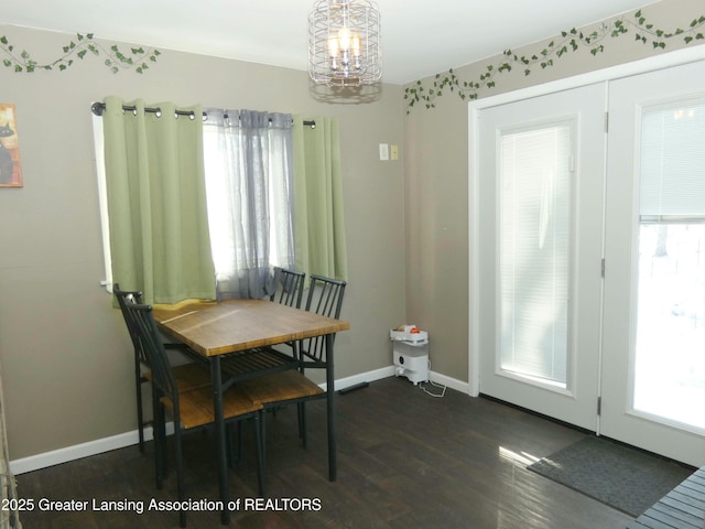 dining area with dark wood-type flooring and a notable chandelier