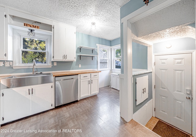 kitchen featuring dishwasher, a textured ceiling, white cabinetry, and sink