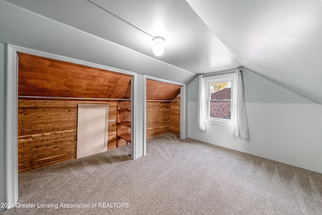 bonus room with wooden walls, carpet floors, and lofted ceiling