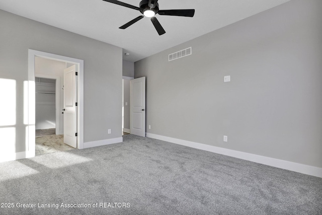 unfurnished bedroom featuring a spacious closet, light colored carpet, and ceiling fan