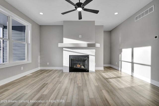 unfurnished living room with light hardwood / wood-style flooring, a fireplace, and ceiling fan