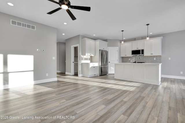 kitchen with sink, white cabinets, pendant lighting, stainless steel appliances, and backsplash