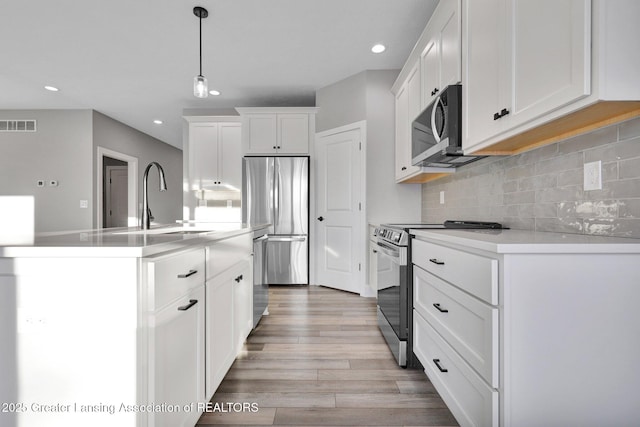 kitchen featuring pendant lighting, sink, appliances with stainless steel finishes, white cabinetry, and tasteful backsplash