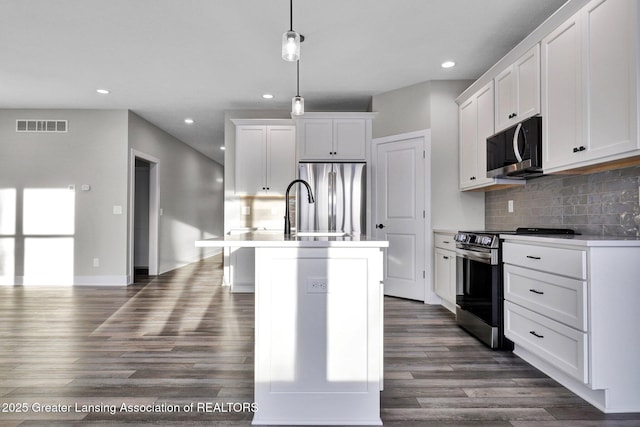 kitchen with decorative light fixtures, a center island with sink, dark hardwood / wood-style flooring, stainless steel appliances, and white cabinets