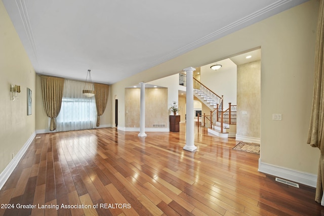 empty room featuring hardwood / wood-style floors, decorative columns, and crown molding