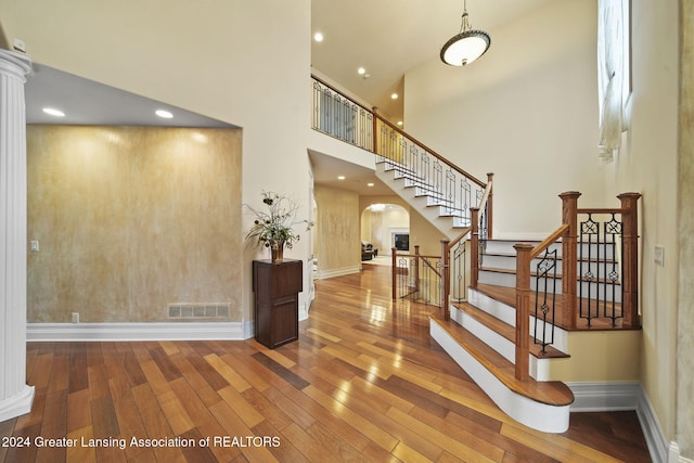 interior space featuring a high ceiling, decorative columns, and hardwood / wood-style floors