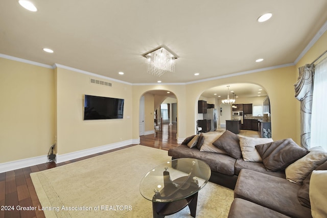 living room with a notable chandelier, dark hardwood / wood-style floors, and ornamental molding