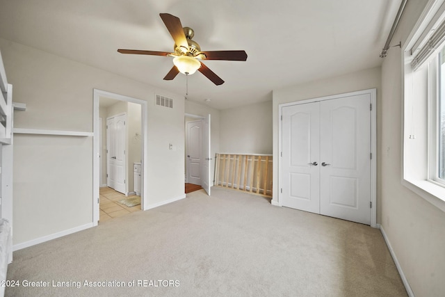 unfurnished bedroom with light carpet, a closet, and ceiling fan