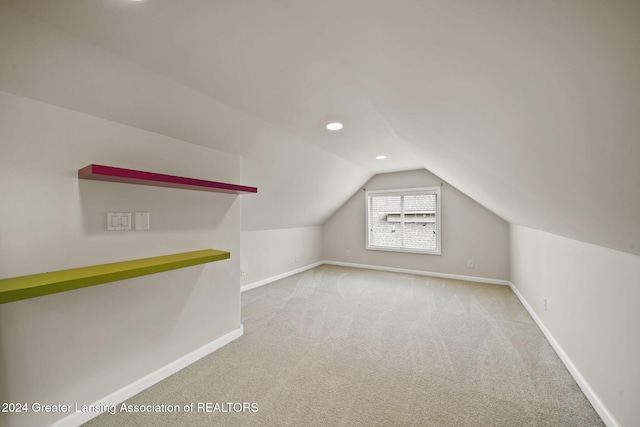 additional living space featuring light carpet and vaulted ceiling