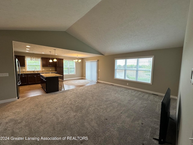 kitchen with pendant lighting, a center island, vaulted ceiling, carpet flooring, and stainless steel fridge