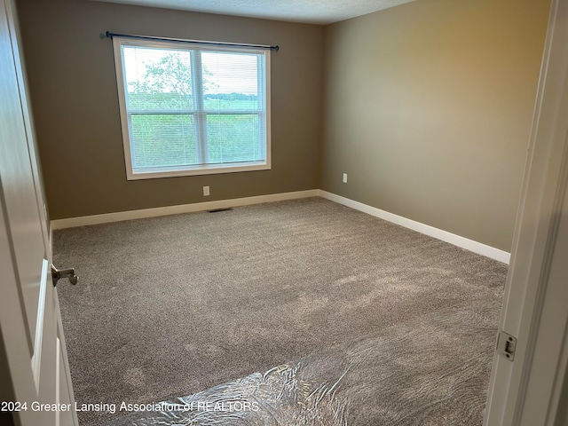 carpeted spare room with a textured ceiling