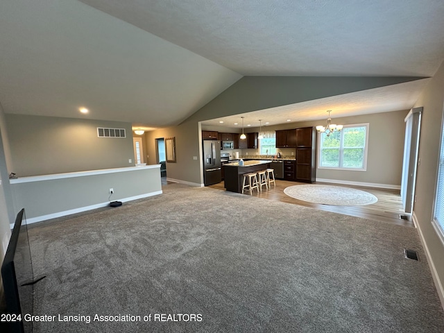 unfurnished living room featuring a chandelier, light colored carpet, and lofted ceiling