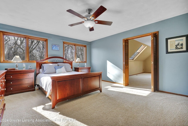 bedroom featuring multiple windows, light carpet, lofted ceiling with skylight, and ceiling fan