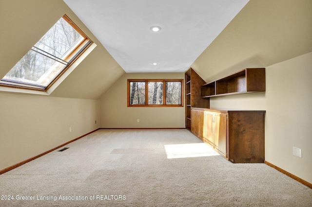 bonus room featuring vaulted ceiling with skylight and light colored carpet