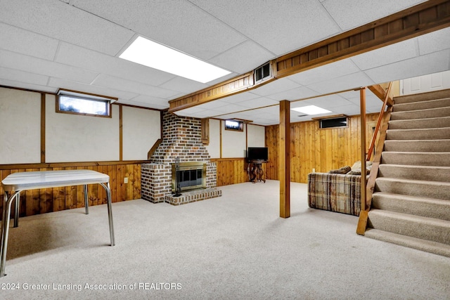 rec room featuring a paneled ceiling, carpet floors, a fireplace, and wooden walls