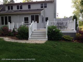 back of house featuring a wooden deck and a yard