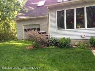 view of side of property with a garage and a lawn