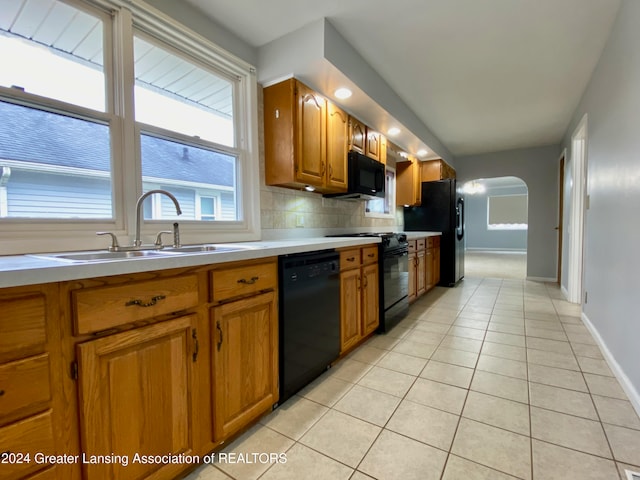 kitchen with decorative backsplash, sink, light tile patterned flooring, and black appliances