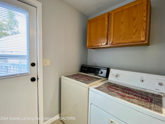 washroom featuring cabinets, a textured ceiling, and washer and dryer