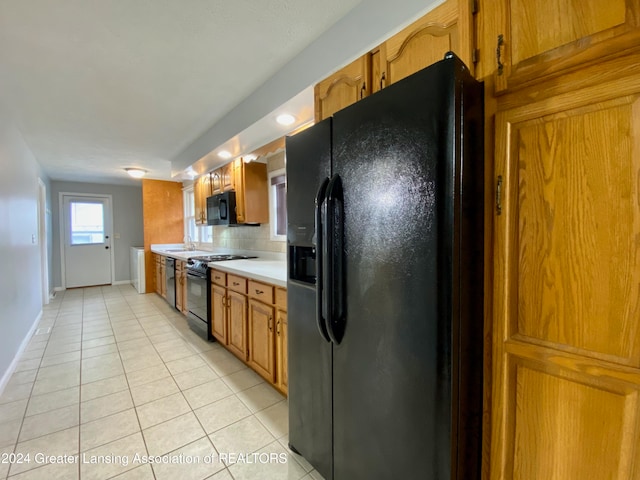 kitchen featuring black appliances, light tile patterned flooring, and backsplash