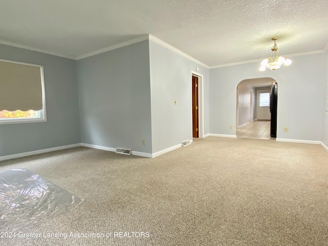 unfurnished room featuring a textured ceiling, a notable chandelier, crown molding, and light carpet