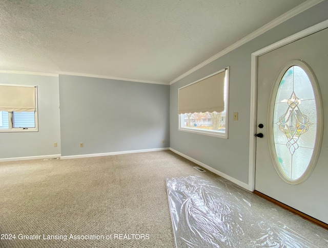 carpeted foyer entrance featuring plenty of natural light, ornamental molding, and a textured ceiling