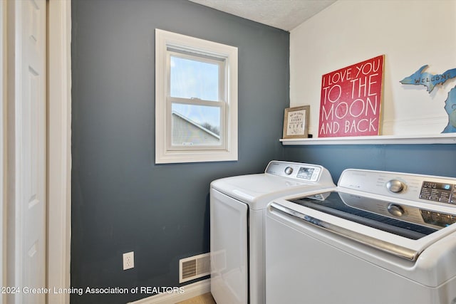 clothes washing area with washer and dryer and a textured ceiling