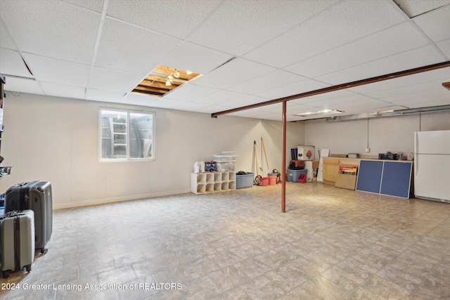 basement featuring white fridge and a drop ceiling