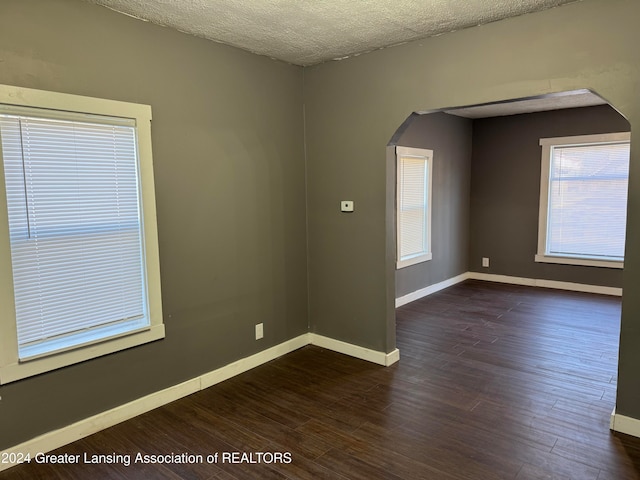 empty room featuring a textured ceiling and dark hardwood / wood-style flooring