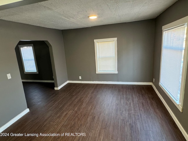 empty room with a textured ceiling and dark hardwood / wood-style floors