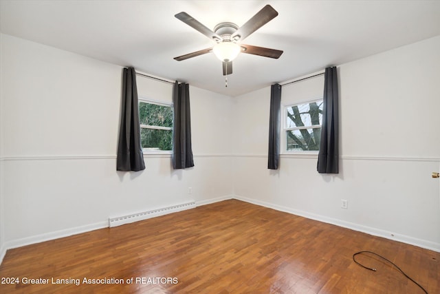 empty room with a wealth of natural light, ceiling fan, hardwood / wood-style flooring, and a baseboard heating unit