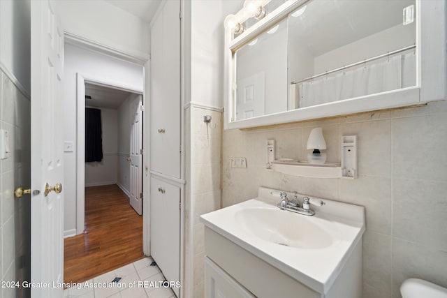 bathroom featuring vanity, hardwood / wood-style flooring, tile walls, and backsplash