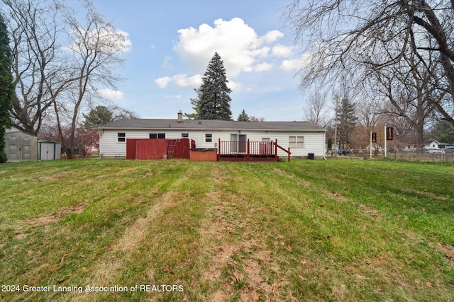 rear view of property featuring a yard, a shed, and a deck