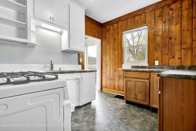 kitchen featuring wooden walls, white gas stove, and sink