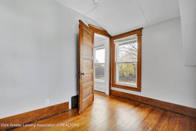 unfurnished room featuring hardwood / wood-style flooring and lofted ceiling