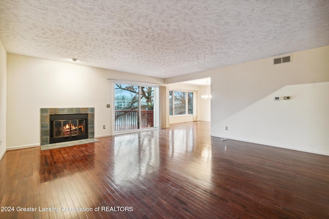 unfurnished living room featuring a tile fireplace, wood-type flooring, and a textured ceiling