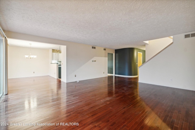 spare room featuring a textured ceiling, hardwood / wood-style flooring, and a notable chandelier