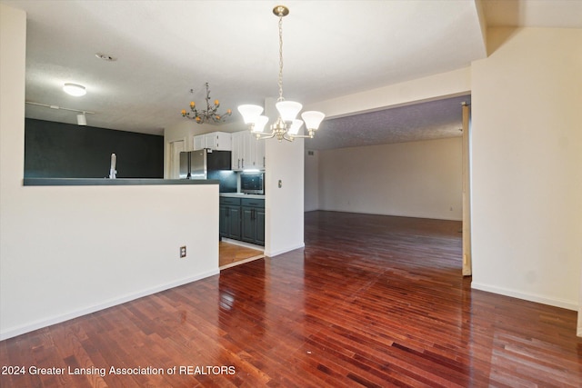 interior space with a textured ceiling, dark hardwood / wood-style floors, and a notable chandelier