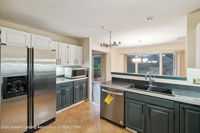 kitchen with stainless steel appliances, sink, pendant lighting, a notable chandelier, and white cabinetry