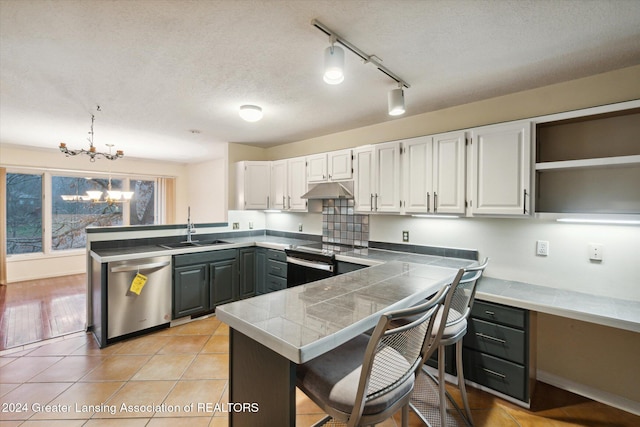 kitchen featuring sink, stainless steel appliances, a notable chandelier, pendant lighting, and white cabinets