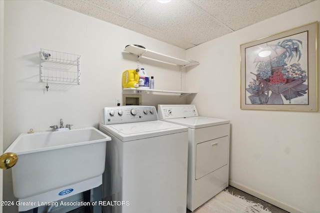 clothes washing area with separate washer and dryer and sink