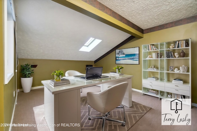 carpeted office space featuring vaulted ceiling with skylight and a textured ceiling