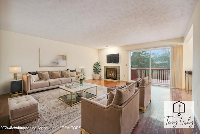 living room featuring a textured ceiling, wood-type flooring, and a fireplace