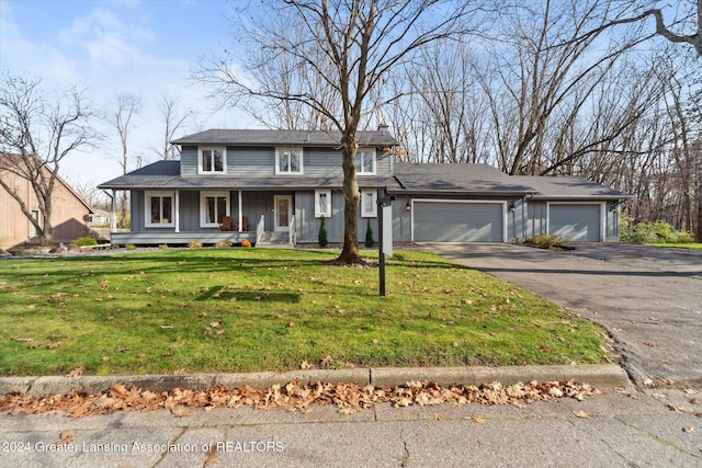 view of front of house featuring covered porch, a garage, and a front lawn